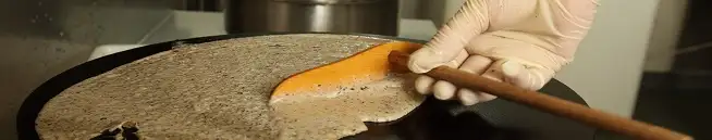 Crêpier étalant sa pâte à crêpe sur une billig Crêpier étalant sa pâte à crêpe sur une billig